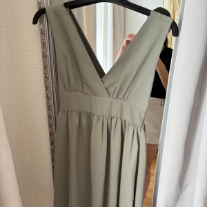 Ljusgrön långklänning från Bubbleroom - Supersnygg ljusgrön långklänning från Bubbleroom med v-ringning och breda axelband. Klänningen har omlottkänsla och knyt i ryggen för extra detalj. Perfekt för dig som vill ha en flowy och elegant look i sommar. OBS! Liten i storlek, mer som en S