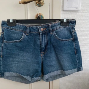 KÖP FRÅN MIN VINTED - Klassiska blå jeansshorts med uppvikta benslut och femficksmodell. De har normal passform och bälteshällor i midjan. Perfekta för varma dagar och enkla att matcha med allt. Snygg denim-look som aldrig går ur tiden.