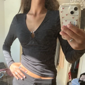 Svart långärmad topp med v-ringning H&M - Svart långärmad topp från H&M i stretchigt material. Snygg v-ringning med liten cut-out och rynkdetalj framtill. 