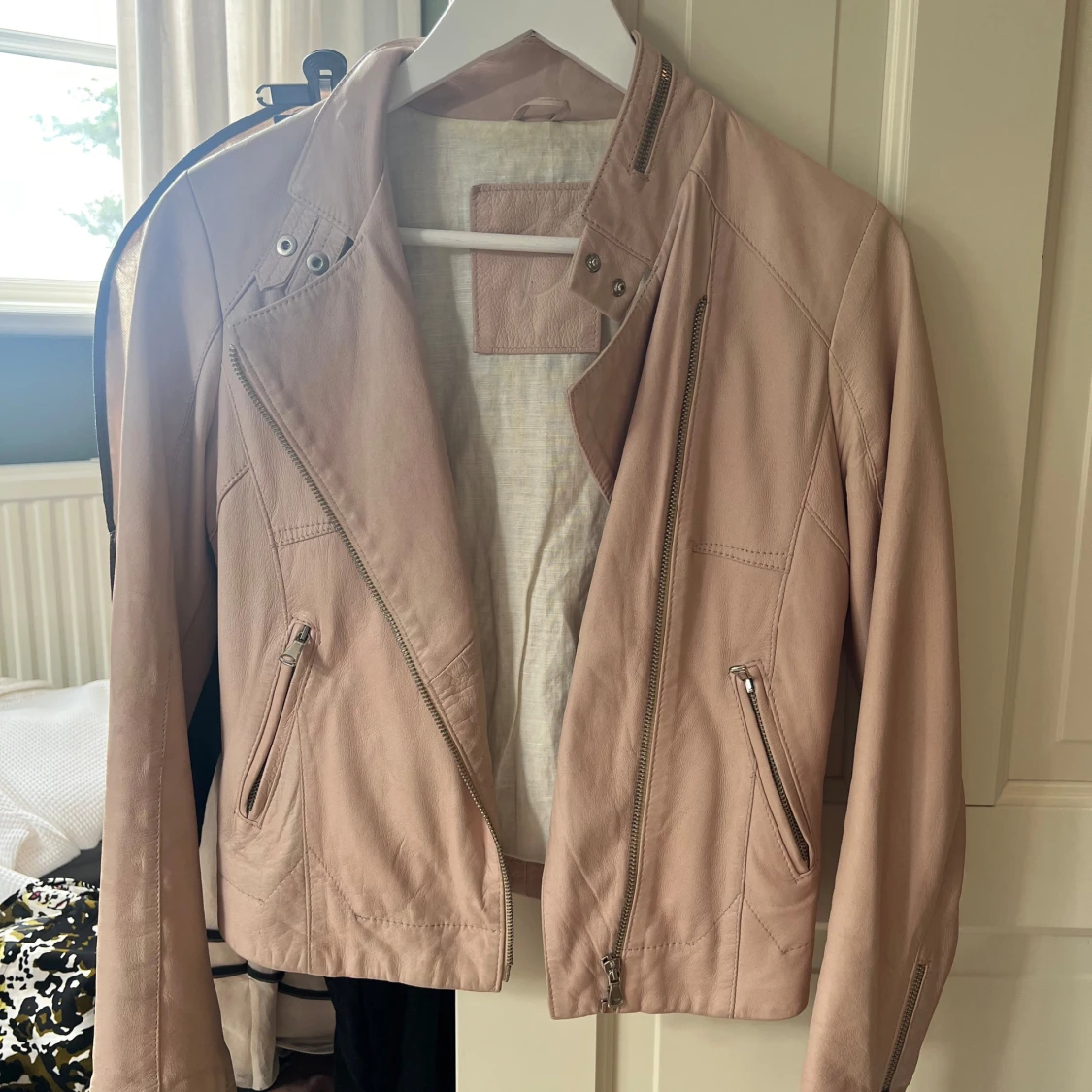 Ljusrosa skinnjacka med dragkedjor