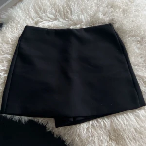 Svarta skorts - Enkel och stilren svarta skorts med rak passform. Kjol fram och shorts bak. Tidlös design som funkar till många olika looks.