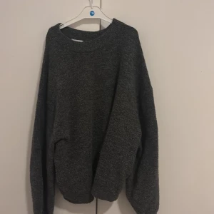 Mörkgrå stickad tröja från H&M - Mysig mörkgrå stickad tröja från H&M med oversized passform och rund halsringning. Perfekt för lager-på-lager och chill dagar. Långa ärmar och mjukt material som känns skönt mot huden.