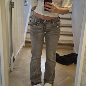 Lågmidjade bootcut jeans med strass - Säljer mina superfina bootcut jeans från Gina tricot! Jeansen har påstrukna strass detaljer på fickor fram och bak. (Går att ta bort.) Avklippta cirka 2 cm (se bild 5), jag är 163 cm. Sparsamt använda! Stl 164