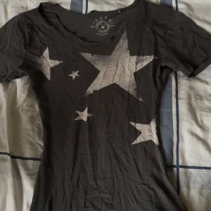 Svart t-shirt med stjärnor från FSBN - mörkgrå t-shirt från FSBN tror ja, är inte säker då jag fick den från turkiet av min moster. var innan baggy men ja har själv sytt in den till slim fit. de står att storleken är MEDIUM men ja har sytt in den så den är numera XS. ja är då 1,54 och den sitter perfekt på mig! ja har sytt den ganska smalt så den kan sitta tight. men överlag fin tröja och skön. det är dock bara uppklippt vid nacken så de är ingen söm där utan att jag bara har klippt så man kan ha den offshoulder!! 
