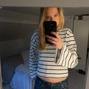 Vit croppad randig tröja - Säljer en vita stickade tröja med mörkblåa ränder. Tröjan har vida ärmar. Tröjan är i nyttskick då jag aldrig den aldrig kommit till andvändning. Skriv om du har några frågor 💓