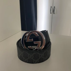 Svart Gucci GG Supreme bälte - Säljer ett svart Gucci GG med ikoniskt dubbelt G-spänne i silver. Bältet har ett diskret mönster med GG-loggor längs hela bandet och är tillverkat i skinn med canvasdetaljer. Perfekt accessoar för att lyfta din outfit. Skriv vid frågor!!!!!