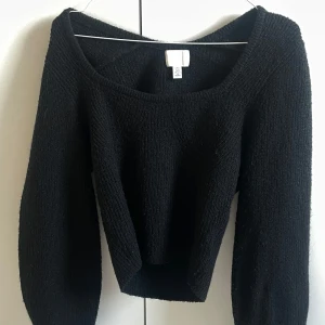 Svart stickad croppad tröja från H&M - Säljer en svart stickad croppad tröja från H&M med fyrkantig ringning och långa ärmar. Perfekt för lager-på-lager och enkel att matcha med olika outfits.