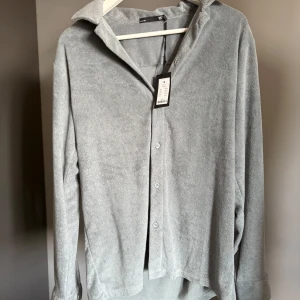 Grönblå frottéskjorta  - Säljer en grönblå skjorta i mjuk frotté material. Skjortan har klassisk krage, knäppning framtill och långa ärmar med manschett. Helt ny med prislapp, skriv för frågor❤️