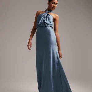 Blå långklänning med halterneck - Helt oanvänd med lapp kvar. Nypris 1100kr. Elegant blå långklänning med halterneck och draperad detalj framtill. Klänningen har en öppen rygg och är tillverkad i ett glansigt, mjukt material som ger ett lyxigt intryck. Perfekt för balen.🌸🌸