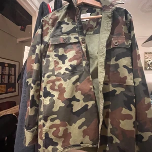 Camouflage overshirt från Samsøe Samsøe - Säljer en snygg camouflagefärgad overshirt från Samsøe Samsøe. Jackan har klassisk krage, två bröstfickor med knappar och raka ärmar. Perfekt för lager-på-lager och streetwear-stil. Nypris ligger på cirka 1200 tror jag men nt säker