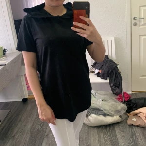 Svart hoodie med dragkedja - Säljer en svart kortärmad hoodie med huva och sned dragkedja på sidan. Tröjan har en avslappnad passform och är perfekt för en cool och enkel stil. Passar till mycket och är superbekväm.