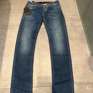 Jeans från Handpicked - Snygga blå jeansbyxor från Handpicked med klassisk femficksdesign och raka ben. Jeansen har kontrastsömmar och en röd patch bak i midjan. Insidan har rutigt tyg och etikett med varumärket. Perfekta för en stilren vardagslook. Nypris ligger på 3000kr, modell på jeansen är Orvieto! 