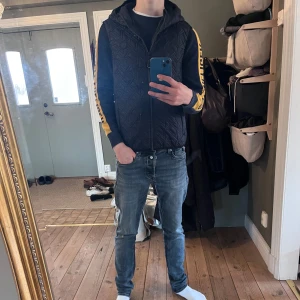 Blå tröja från Tommy Hilfiger med snygga detaljer - Säljer en blå långärmad tröja från Tommy Hilfiger med gula ränder och logotyp längs ärmarna. Klassisk rund halsringning och liten broderad logga på bröstet. Super snygg att stylea med väst🤩