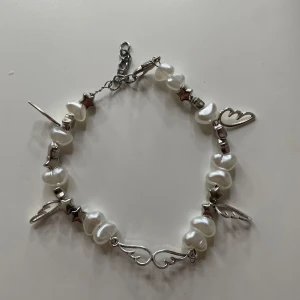 Pärlarmband med silverfärgade detaljer och berlocker - Unikt armband med oregelbundna vita pärlor, silverfärgade stjärnor och hjärtan samt dekorativa berlocker. Perfekt accessoar för att lyfta din stil med en mix av sött och edgy.