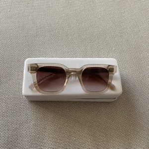 Beige fyrkantiga solglasögon från Chimi - Snygga solglasögon från Chimi i en transparent beige färg med fyrkantig form. Glasen är tonade i brunt och bågarna är tillverkade i plast. Perfekta för soliga dagar och levereras med originalfodral.