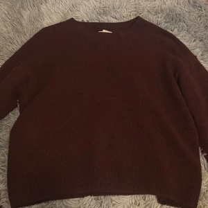 Vintöd/Mörkbrun stickad tröja från H&M - Mysig vinröd/mörkbrun stickad tröja från H&M med rund halsringning. Tröjan har lång ärm och en enkel, klassisk design som passar perfekt till kyligare dagar.