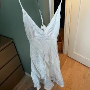 Vit omlottklänning med smala axelband - En vit kortklänning från Zara med omlott och smala axelband i storlek xs/S Justerbar knytning i ryggen❤️. (Den behövs strykas därav hur skrynklig den är och det är även en liten fläck som framgår på bilderna men tror den kan gå bort i tvätten) 