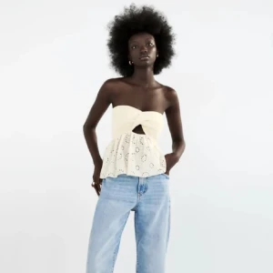 Trendig tubtopp från Zara - Säljer en söt vit  tubtopp med volanger från Zara med virkad överdel och broderade blommor på den nedre delen. Toppen är inte använd så mycket så den är i ett väldigt bra skick. För fler bilder skriv privat💕