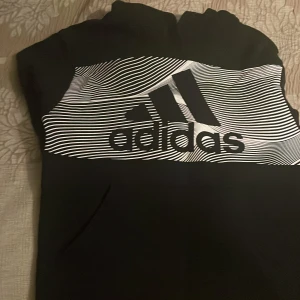 Svart addidas set - Svarta träningsbyxor från Adidas med vit logga på låret och dragsko i midjan. Byxorna har en sportig look och är perfekta för träning eller chill. Tillverkade i ett mjukt och stretchigt syntetmaterial.