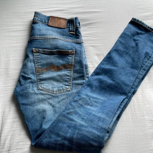 Blå jeans från Nudie Jeans - Säljer ett par klassiska blå jeans från Nudie Jeans i storlek W27 L32. Jeansen är använd ett par gånger och säljer de eftersom de inte passade mig. De är i nyskick och nypris ligger på 1599. Hör av er vid frågor eller funderingar!
