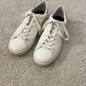 Vita sneakers från Björn Borg - Säljer ett par klassiska vita sneakers från Björn Borg med snygga guldfärgade detaljer på hälen. Skorna har snörning och är tillverkade i syntetmaterial. Perfekta för en stilren och enkel look. Använda ett fåtal gånger med lite tecken på användning som visas på bilderna. Säljer eftersom de blivit för små💓 Pris kan diskuteras