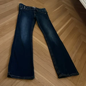 Mörkblå bootcut jeans från Gina  - Snygga mörkblå jeans med bootcut passform och tydliga kontrastsömmar. Klassisk femficksmodell med knapp och dragkedja framtill. Jeansen har en lätt tvättad look och detaljerade bakfickor.