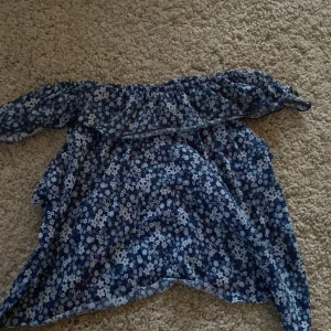 Blommig blå klänning från H&M - Supersöt blå klänning från H&M med vitt blommönster. Klänningen har offshoulder-modell och är perfekt för vår och sommar. Lätt och luftig, passar till många tillfällen. Säljes i storlek 122/128.