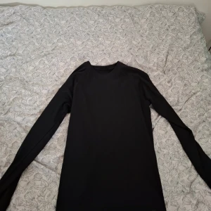 Svart långärmad underställ från McKINLEY - En svart långärmad underställ från McKINLEY. Tröjan har en enkel och stilren design med rund halsringning och är tillverkad i ett ribbat material som ger en skön passform. Perfekt för lager-på-lager eller som basplagg.