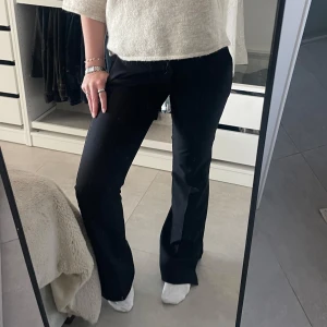 Svarta kostymbyxor - Säljer ett par svarta kostymbyxor med bootcut passform från bikbok. Lågmidjade och med slits längst ner, super snygga!! Som nya eftersom de inte använts mycket alls. 