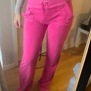 Rosa juicybyxor - Säljer ett par rosa mjukisbyxor från Juicy Couture. Materialet är handuks material  och modellen är loose med raka ben, perfekt för chill dagar. Byxorna har dock  tappat en metall grej på snörningen. .