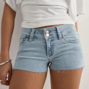 Helt nya Nelly shorts - Snygga ljusblå jeansshorts med rå kant och dubbla knappar framtill. Baktill finns coola fickor med rosa zigzag-broderi som ger extra edge. Klassisk femficksmodell och bälteshällor. 