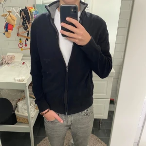 Svart kofta med dragkedja - En svart kofta med hel dragkedja och ståkrage. Tröjan är i mjukt material, har ribbade muddar och en enkel, clean look. Perfekt för lager-på-lager och funkar till de flesta outfits.