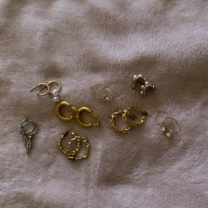 Mix av örhängen i guld och silver - Säljer flera olika örhängen i både guld- och silverfärg. Blandningen innehåller hoops, örhängen med pärlor, små hängen och detaljerade former. Perfekt för dig som gillar att variera din stil och mixa olika smycken. 30kr/par 