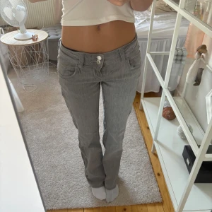 Grå bootcut jeans med låg midja - Säljer ett par grå jeans med snygg bootcut och låg midja. De har klassisk femficksdesign och två knappar framtill. Materialet är jeans och passformen är normal, perfekt för dig som gillar en avslappnad stil. Storlek 146💓