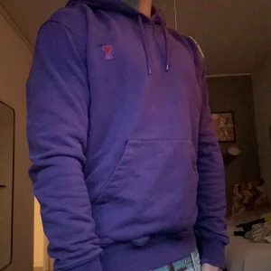  hoodie från Ami Paris - Säljer en snygg hoodie från Ami Paris med klassisk huva och snörning. Tröjan har en stor magficka och ett litet rött Ami-hjärta broderat på bröstet. Materialet är mjuk bomull och passformen är normal. Pris kan diskuteras vid snabb affär