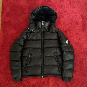 Moncler Maya - Intressekoll på min Moncler Maya. Den är perfekt för vintern med sitt quiltade mönster och långa ärmar. Jackan har en dragkedja framtill och en huva för extra skydd mot kylan. Den är i nyskick och kommer med originalpåse. Den har både NFC scan och QR scan🖤
