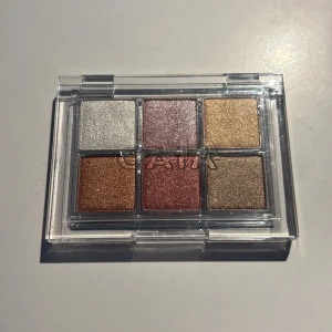 CAIA ögonskuggspalett med metallic - Snygg ögonskuggspalett från CAIA med sex skimrande metallicfärger: silver, roséguld, guld, koppar, vinröd och brons. Perfekt för att skapa både mjuka och intensiva looks. Kommer i en smidig transparent plastförpackning.❤️