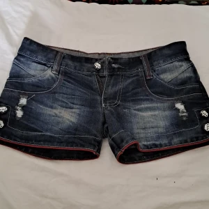 Mörkblåa G-rise jeansshorts yk2 style - Coola mörkblå jeans shorts som är väldigt low waisted. Röda detaljer och många detaljer allmänt. Köpt från en marknad i Thailand.