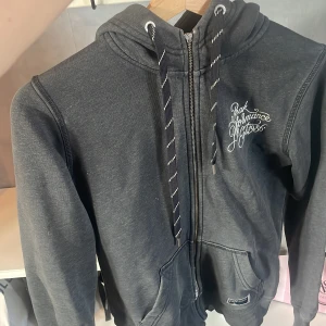 Mörkgrå hoodie från Peak Performance - Säljer en mörkgrå hoodie från Peak Performance med broderad logga på bröstet och patch vid fickan. Tröjan har huva med snörning, dragkedja hela vägen och två stora fickor fram. Insidan är mjuk och fleecefodrad, perfekt för kyliga dagar. Tröjan är änvänd och har defekter men inte några större defekter!❤️