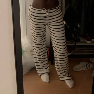 Randiga vita mjukisbyxor  - Säljer ett par vita mjukisbyxor med svarta horisontella ränder och snörning i midjan. Byxorna har en loose passform och är riktigt sköna att chilla i. Perfekta för att hänga hemma eller dra till kompisar. Materialet känns mjukt och stretchigt. DE ÄR stora storlek