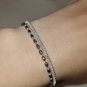Dubbel silverfärgat armband - Snyggt dubbelarmband i silverfärg med en kedja av små ovala pärlor och en glittrig kedja. Perfekt accessoar för att lyfta din outfit.