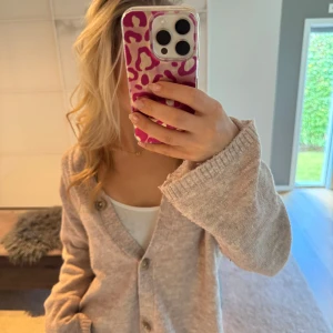 Beige stickad kofta med knappar - Mysig beige stickad kofta med v-ringning och stora knappar framtill. Koftan är från lager 157 och kommer helt enkelt inte till användning. Storleken är M men passar mig som annars bär Xs