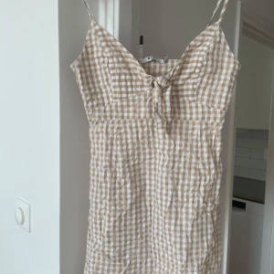 Beige och vit rutig klänning NA-KD - Superfin kort klänning från NA-KD i beige och vitt rutigt mönster. 