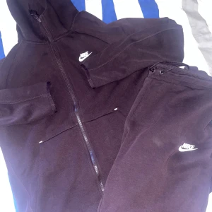 Svarta mjukisbyxor från Nike - 500 för båda tillsammans. Svarta mjukisbyxor från Nike med klassisk logga i vitt på benet. Byxorna har dragsko i midjan för skön passform och är gjorda i mjukt bomullsmaterial. Perfekta för chill eller träning, loose fit och riktigt bekväma.