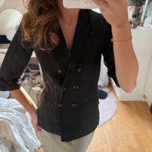 Svart kavaj blus med trekvarts ärm - Så himla fin svart kavaj med trekvarts ärmar och knappar i skepparkavajs modell. Dubbelknäppta. I så fint skick och lite tjockare linne tyg med vaddering lätt i axlarna