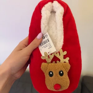 Röda juliga ballerinaskor med renmotiv - Supermysiga röda ballerinaskor med fluffigt vitt foder och en gullig renapplikation framtill med glittriga horn. Perfekta för att maxa julstämningen hemma! Yttermaterialet är mjukt och insidan är riktigt skön och varm. Står ej för frakt 