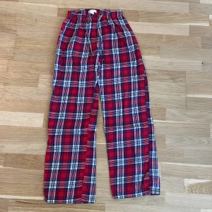Röd-rutiga pyjamasbyxor från Gina Tricot, 146/152 - Röd-rutiga pyjamasbyxor från Gina Tricot i storlek 146/152. De har en elastisk midja med snörning och är gjorda i bomull. Perfekta för chill dagar eller när du vill ha en avslappnad look. 