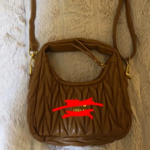 Brun quiltad axelväska med dragkedja - Säljer en jättefin väska ” mi* mi* ” ej äk1@ . Sjukt bra läder , mini väska som passar till allt. Skriv för fler bilder 