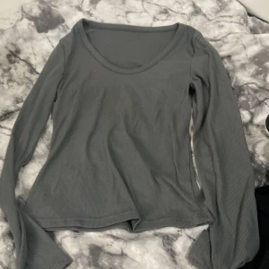 Grå ribbad långärmad tröja Dazy - Snygg grå långärmad tröja från Dazy x StarSeries i storlek S. Tröjan har ribbad struktur och en rundad, lite djupare halsringning. Perfekt att styla med jeans eller kjol för en chill look. Materialet är mjukt och stretchigt, vilket gör den skön att bära hela dagen.