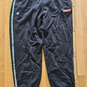 Svarta mjukisbyxor Liverpool FC x Converse helt ny! - Small. Kort version             längd enligt bild      Svarta mjukisbyxor med Liverpool FC-logga broderad på benet och Converse-stjärna på andra sidan. Snyggt mönstrad kant i ljusblått längs benet och tryckt text på höften. Perfekta för chill eller träning, mjukt bomullsmaterial och loose passform.